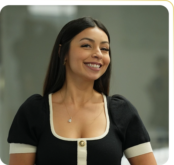Smiling woman with long dark hair wearing a black top with white trim and a necklace.