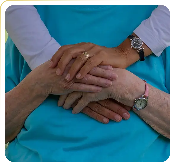Four hands of elderly people gently resting on each other over a blue garment.