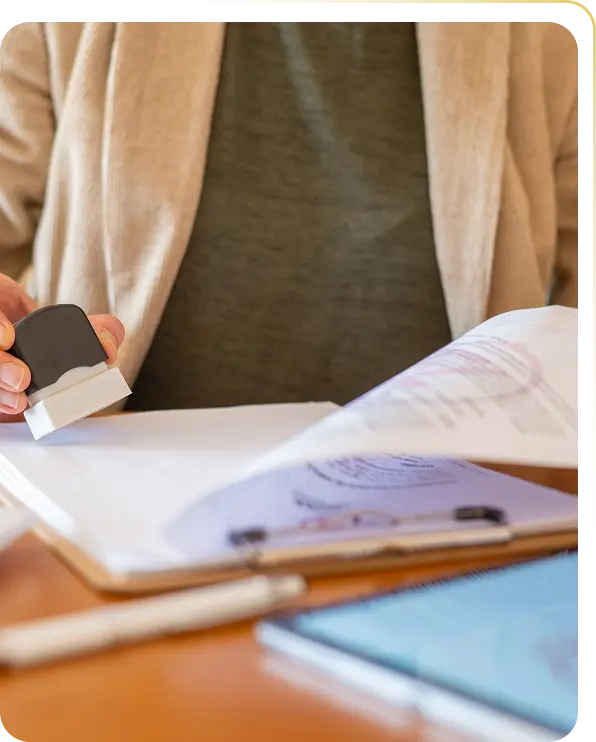 Person stamping a document on a clipboard with a pen and smartphone on the table.