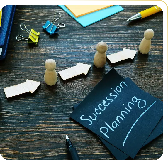 Wooden figures with arrows on a table next to notes labeled 'Succession Planning' and office supplies.