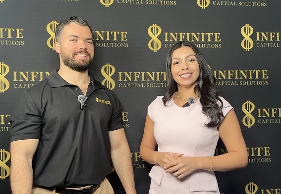 Man and woman smiling and standing in front of black backdrop with Infinite Capital Solutions logos.