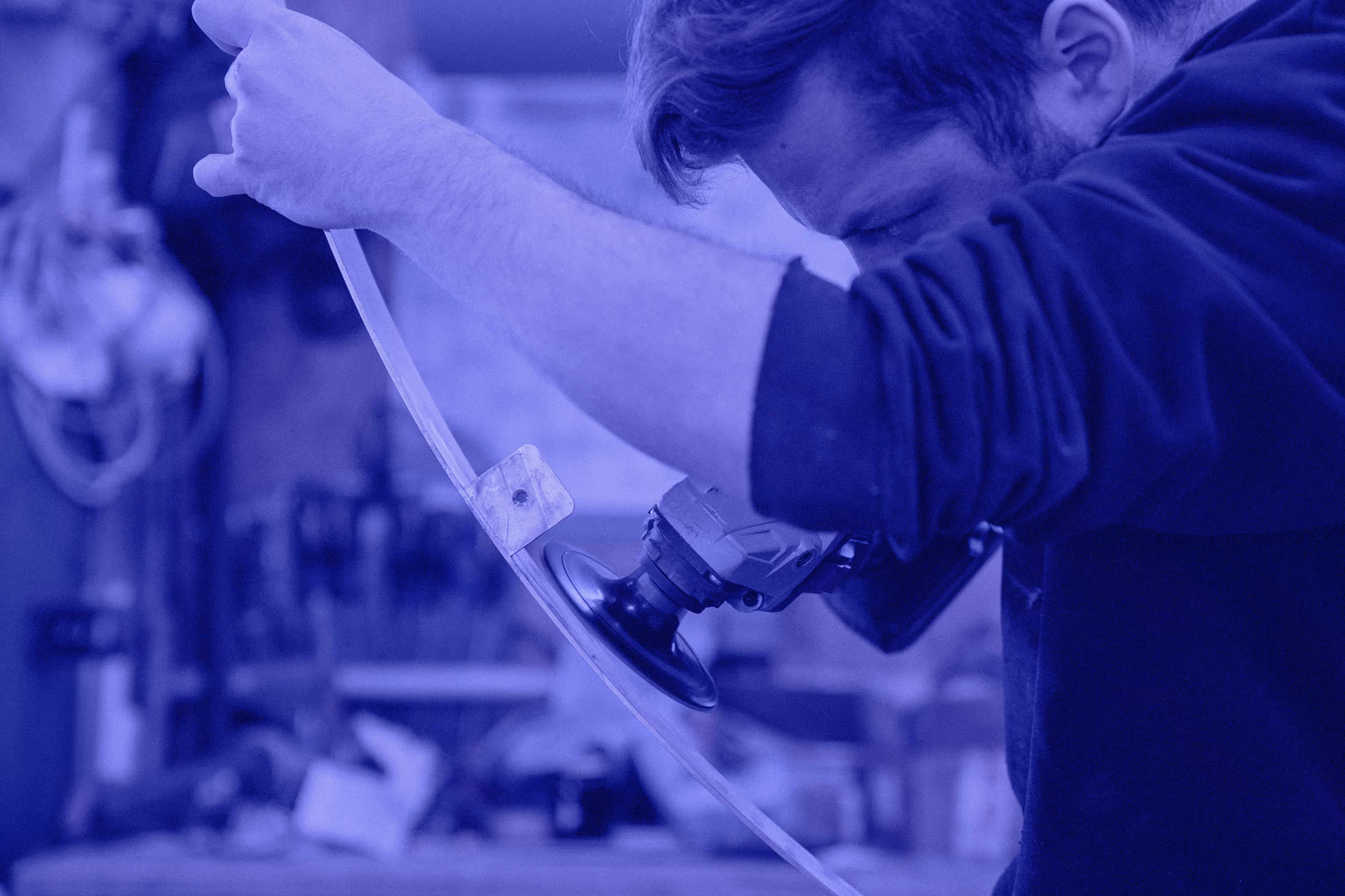 Handwerker schleift mit Winkelschleifer an einem gebogenen Metallstück aus Messing.