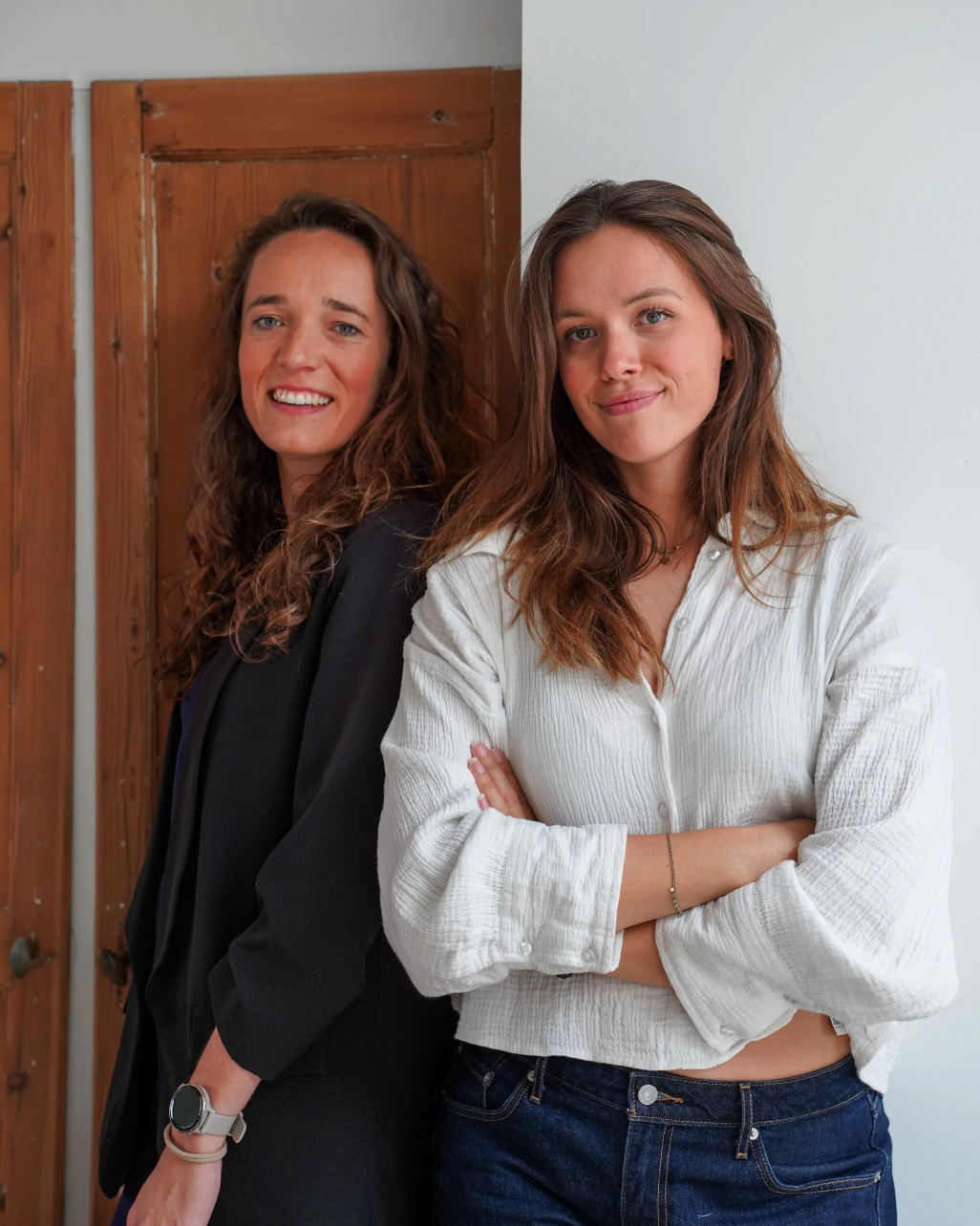 Les deux fondatrices de la commère souriantes, l'une en veste noire, l'autre en chemise blanche, posent côte à côte.