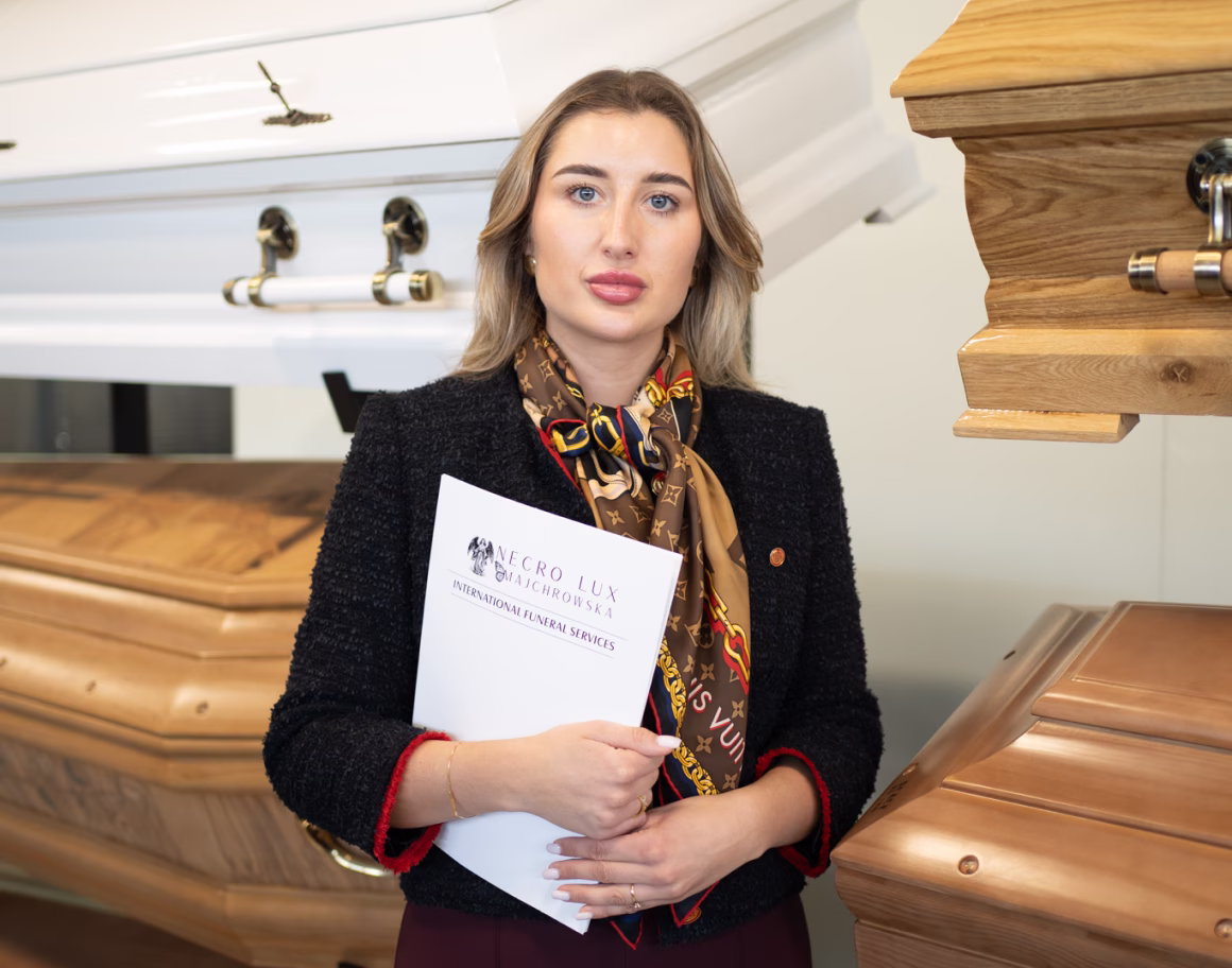 Funeral director showing wooden and white coffins to a couple in a funeral home showroom.