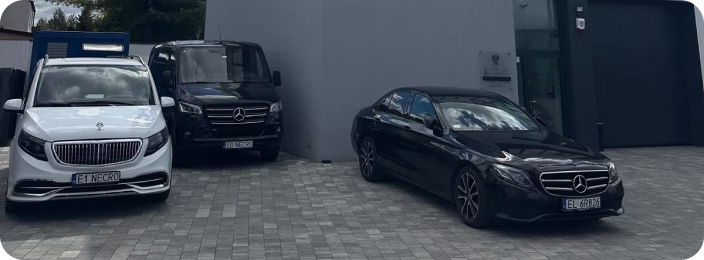 Три автомобілі Mercedes-Benz, припарковані на бруківці біля сірої будівлі.