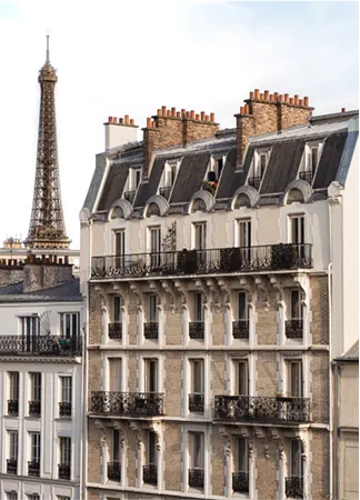 Façade d'un immeuble parisien avec la tour Eiffel en arrière-plan sous un ciel clair.