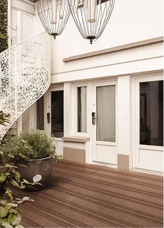 Patio with wooden floor, a large plant pot, white spiral staircase, and two hanging cage lights.