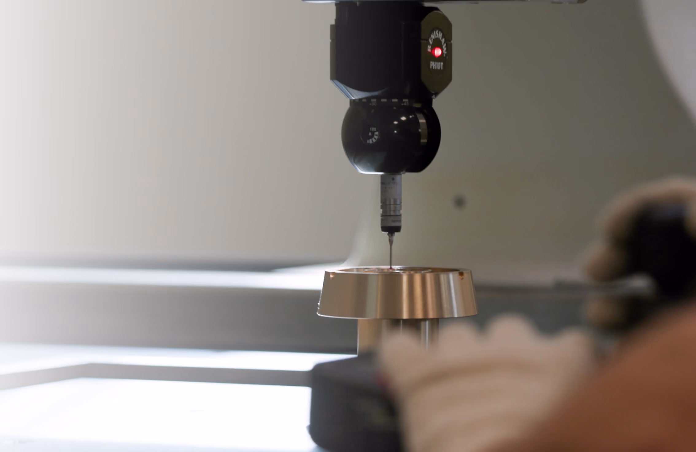 Macchina di misura con sonda che controlla la precisione di un pezzo metallico circolare in fase di lavorazione.