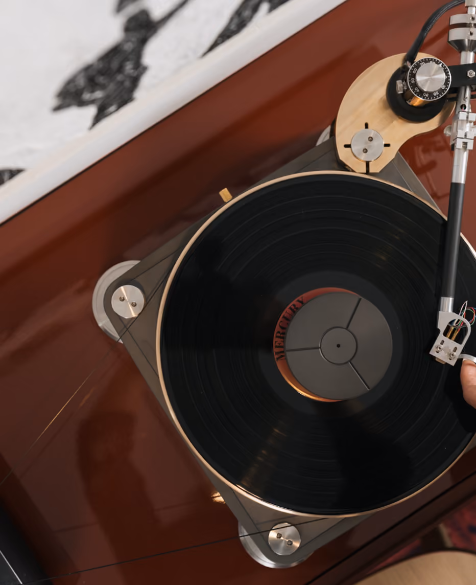 Giradischi vintage con un vinile nero in riproduzione e una mano che regola la testina sul disco.