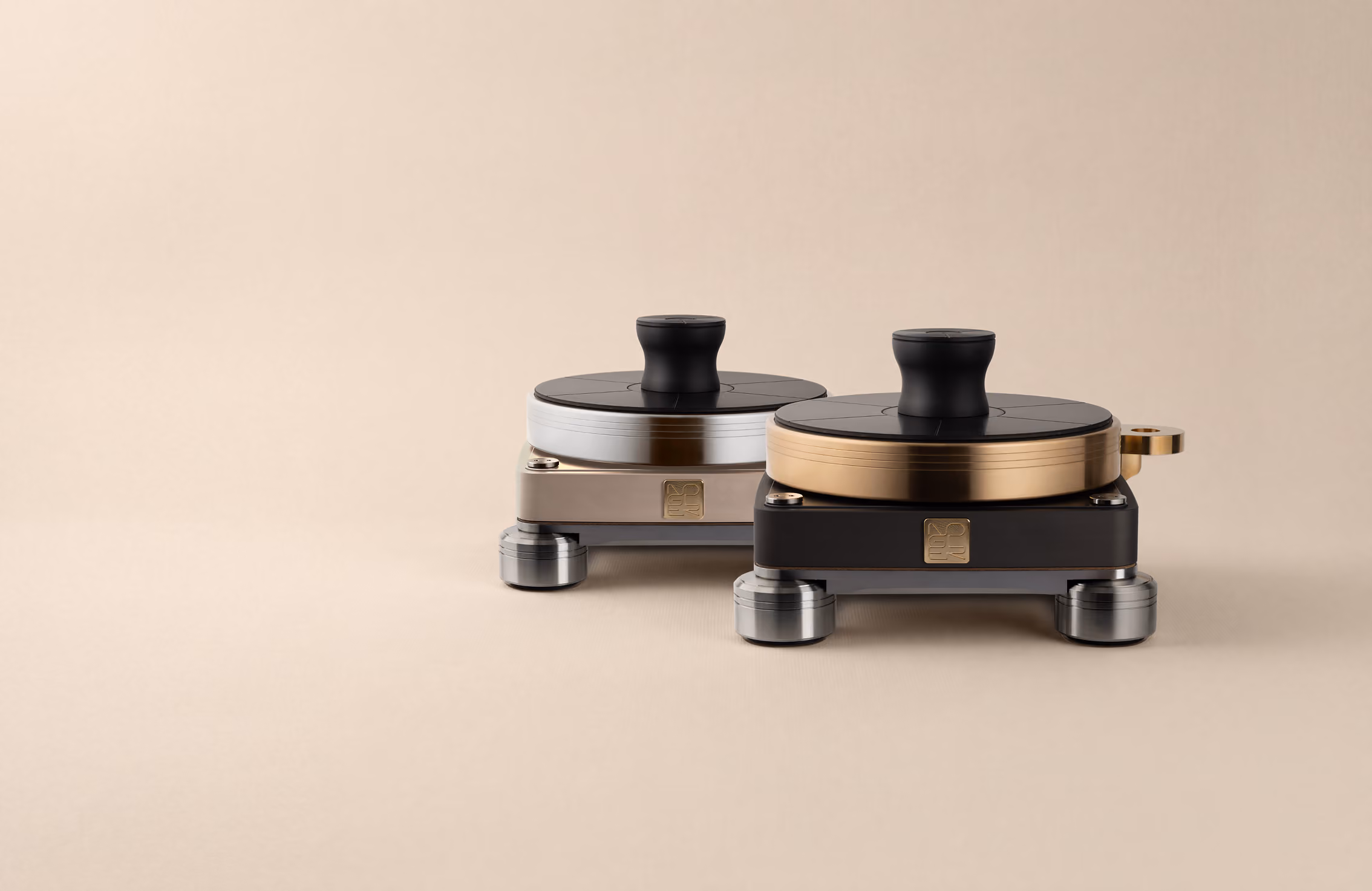 Due dispositivi audiotecnici compatti con manopole nere sopra, uno con bordo dorato e l'altro con bordo argento, su una superficie beige.