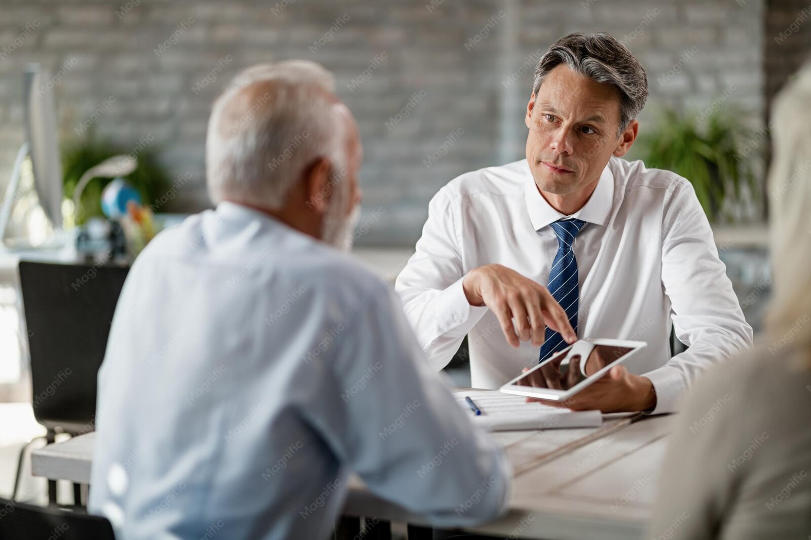 Conseiller en assurance présentant une tablette à des clients