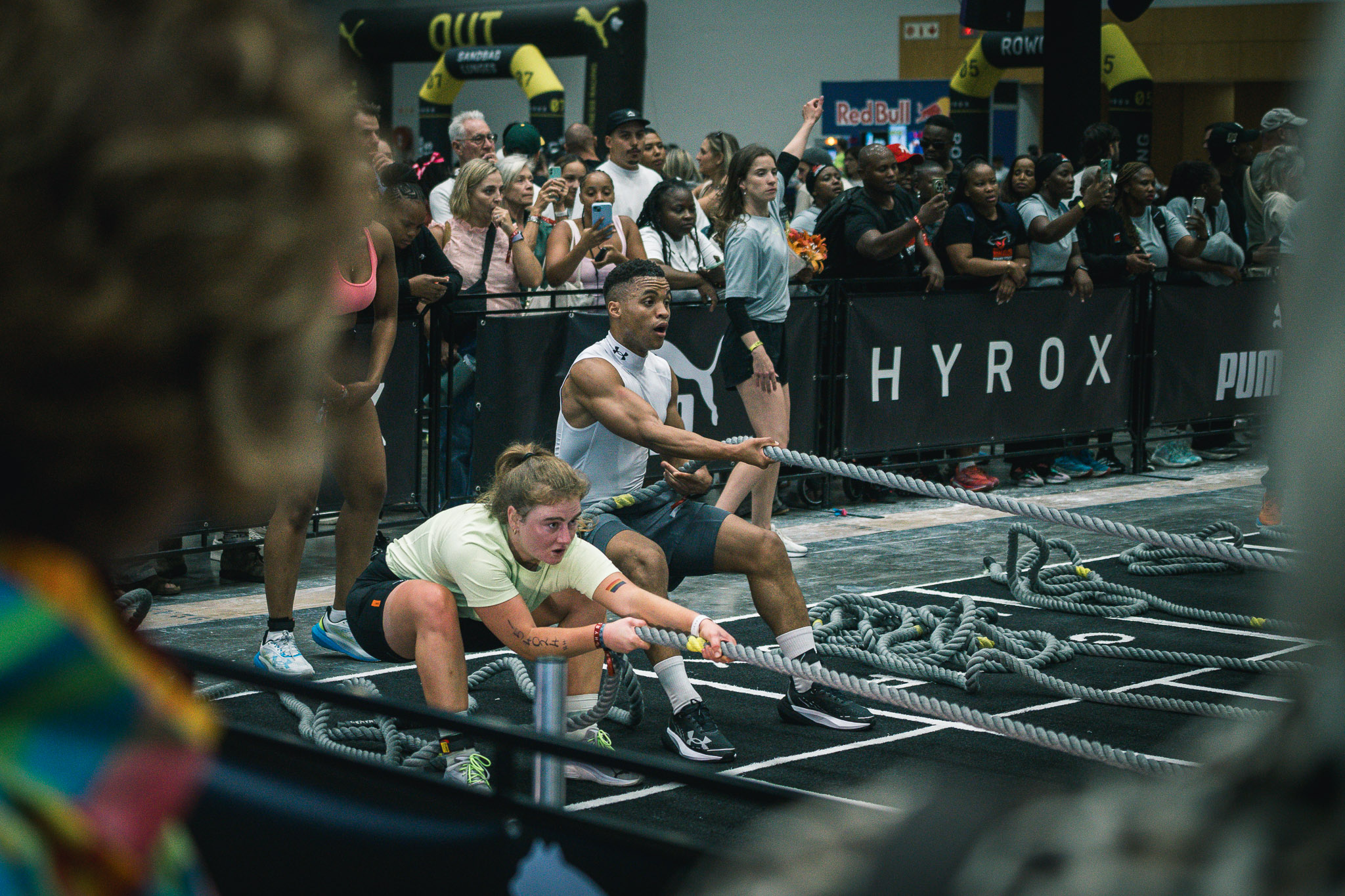 Sports photographer Cape Town — Two athletes pulling rope sleds in HYROX Cape Town doubles category, packed crowd watching