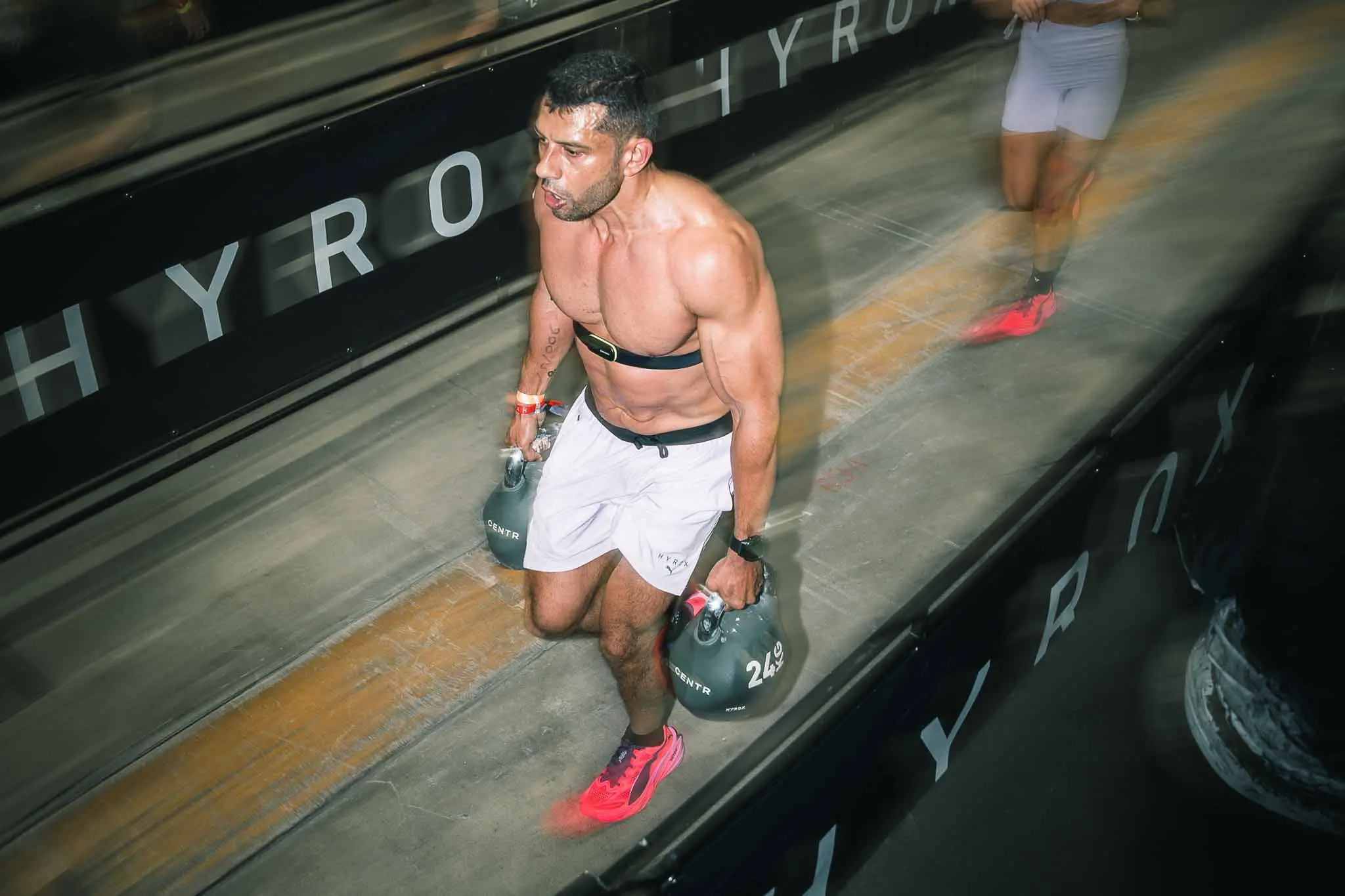 HYROX photographer Cape Town — athlete carrying kettlebells on the HYROX floor at the CTICC