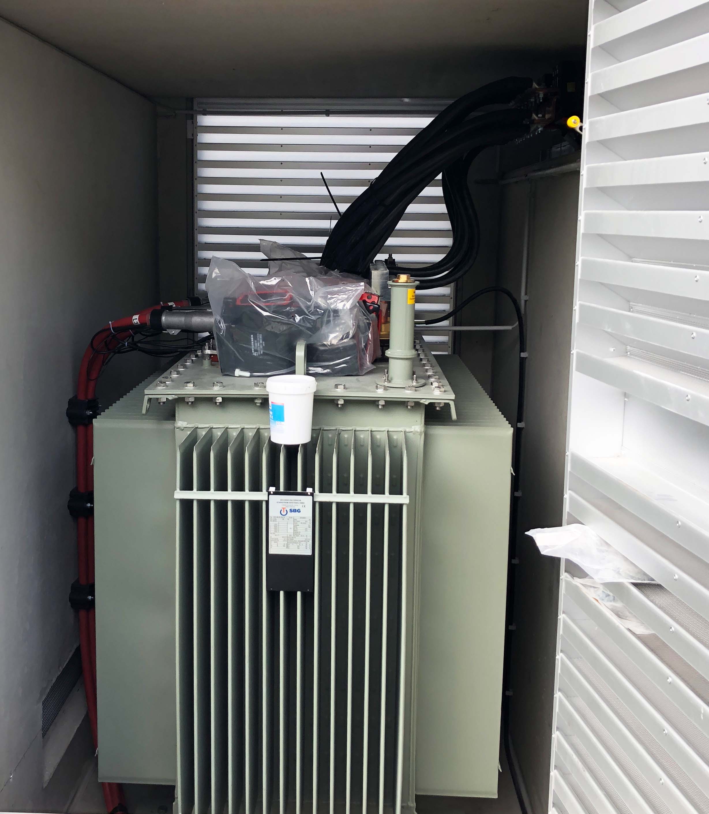 ltransformator mit Kabelanschlüssen im Inneren einer Transformatorenstation während der Installation