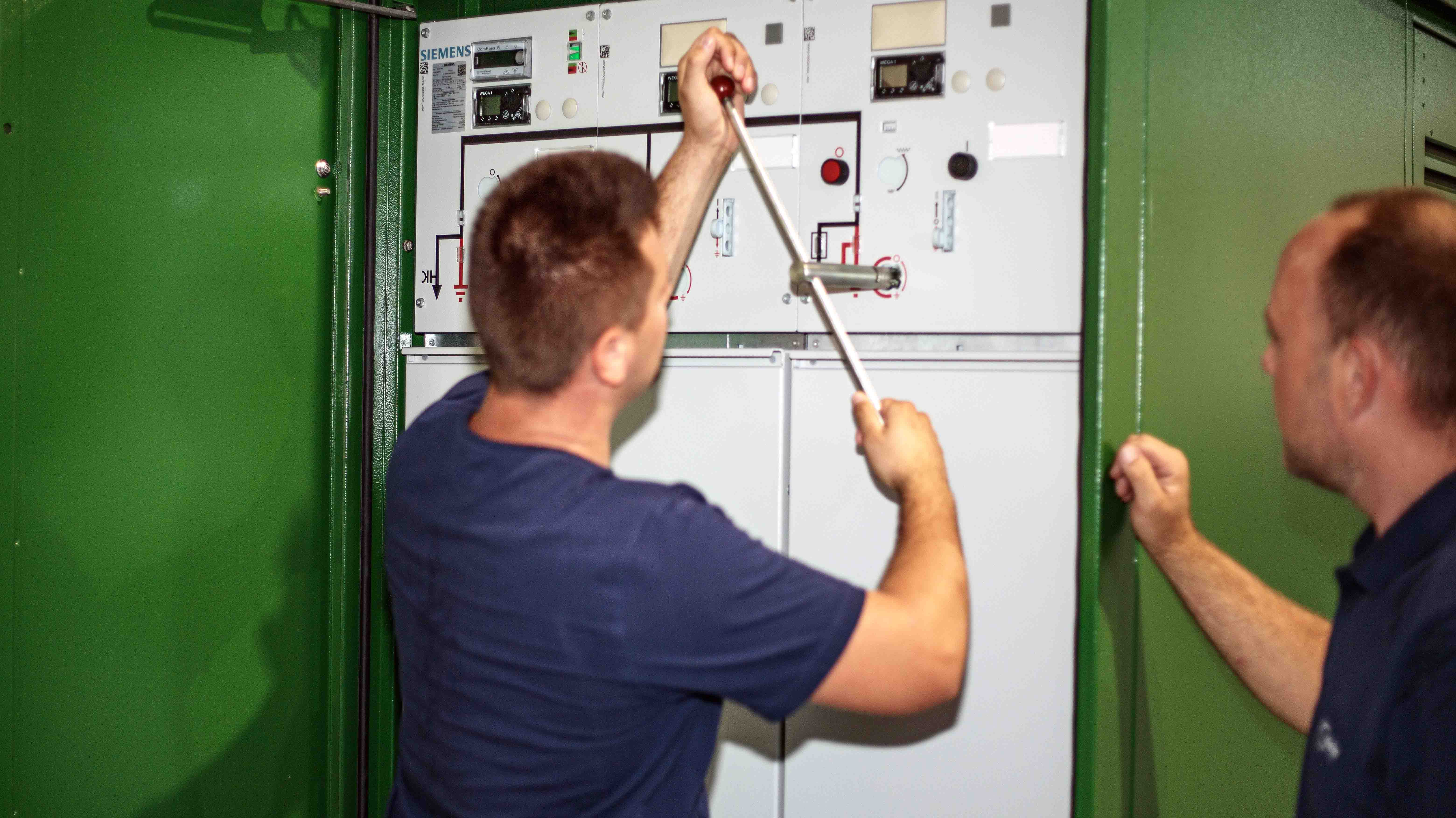 Techniker bedient eine Mittelspannungsschaltanlage mit Schalthebel in einer Transformatorenstation