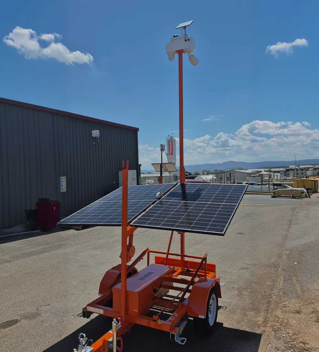 Mobile solar panel trailer with dual panels and a pole-mounted camera under a blue sky.