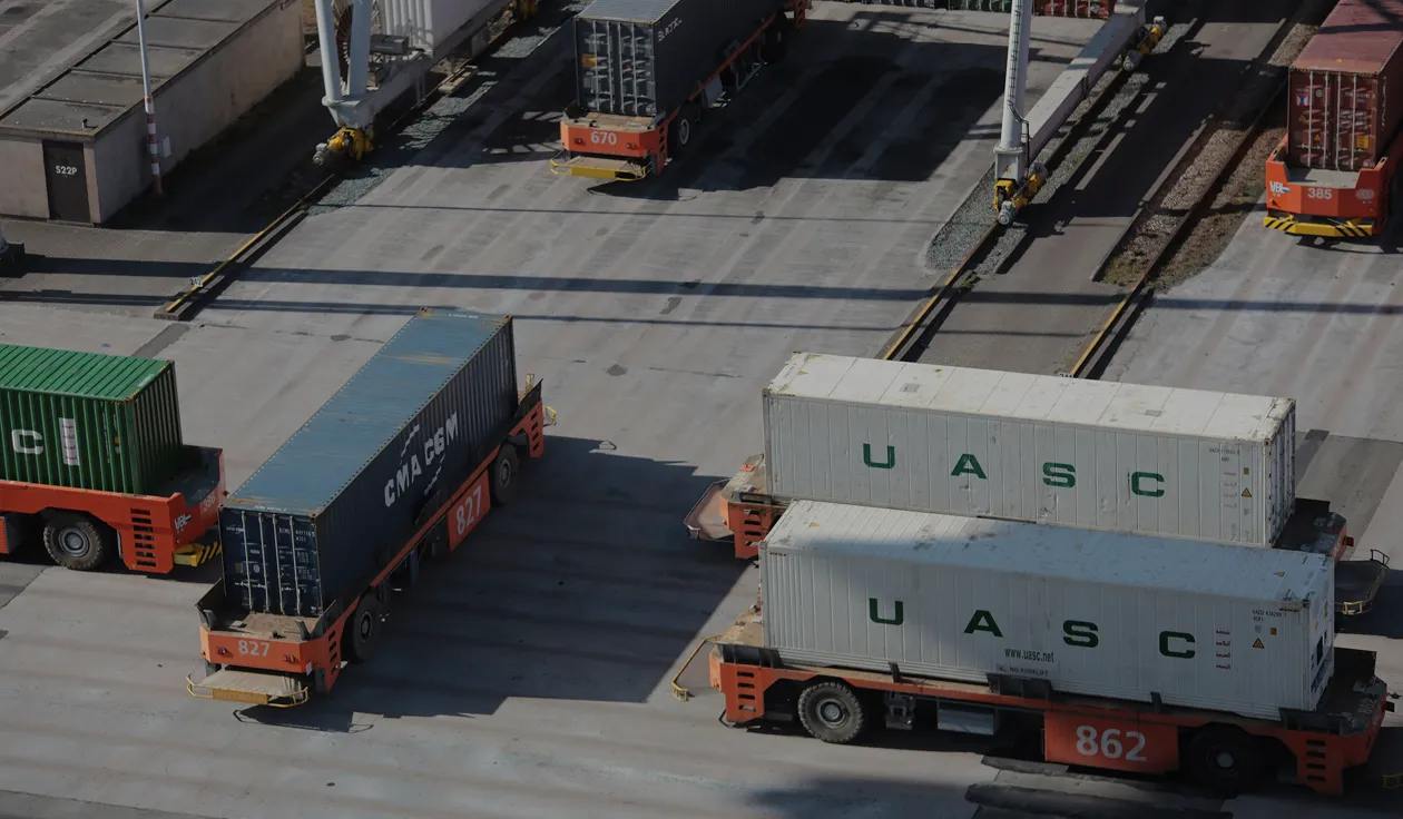 Aerial view of numbered carriers moving shipping containers across a port yard
