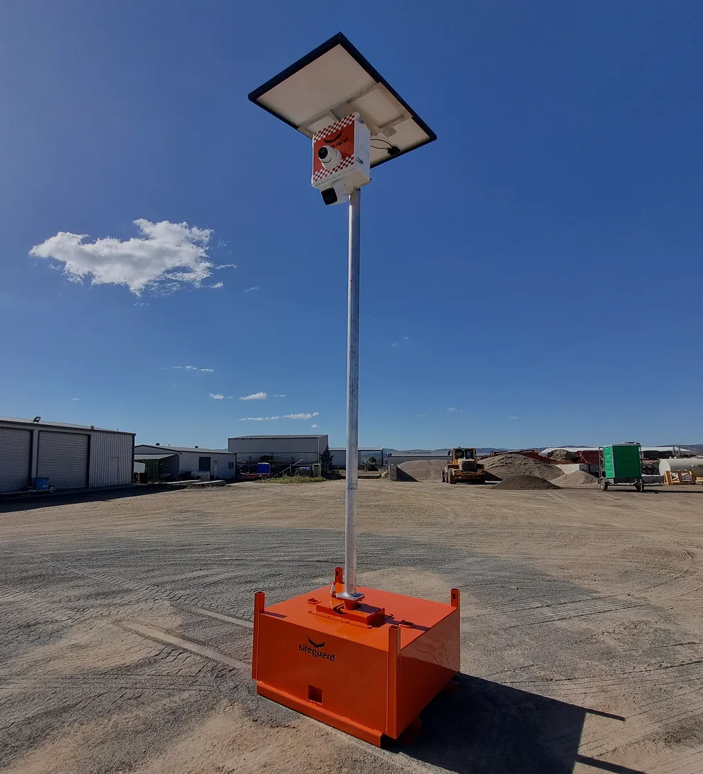 Orange Siteguard solar-powered security camera unit standing on a gravel surface in an industrial yard.
