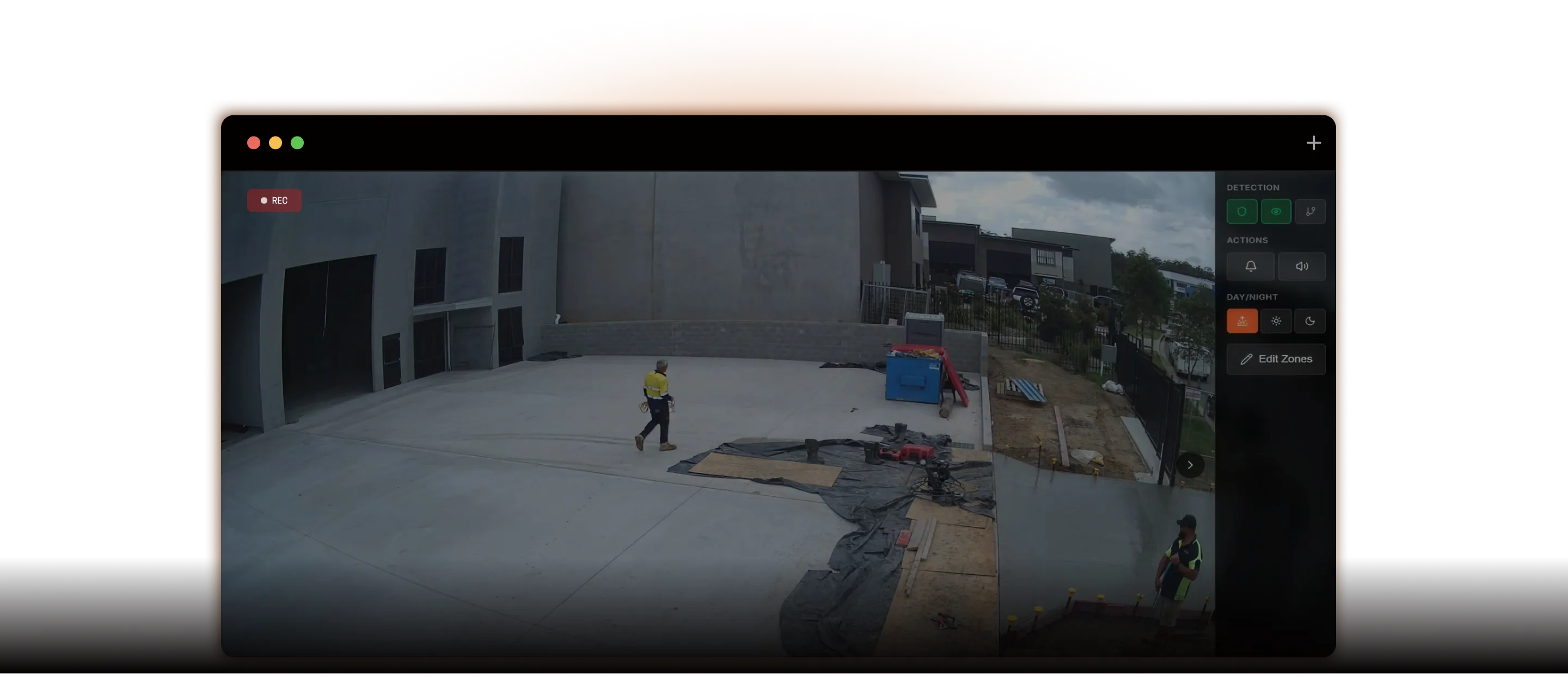 Two workers in high-visibility clothing on a concrete construction site with building and equipment around.