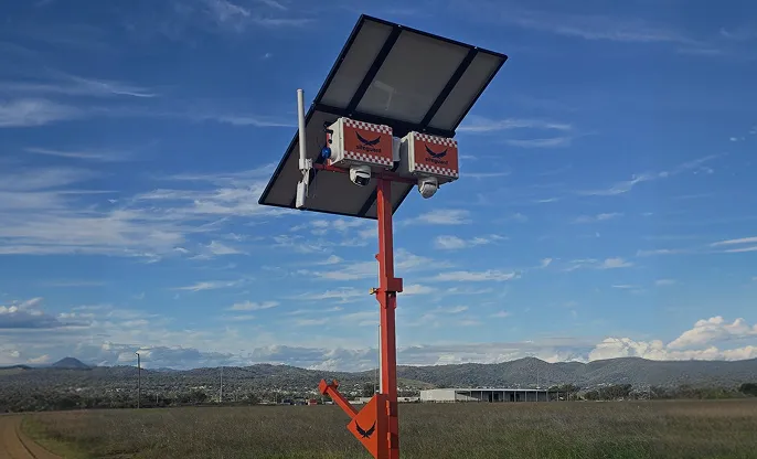 Siteguard solar camera tower with two cameras under a solar panel on an orange mast in an open rural paddock