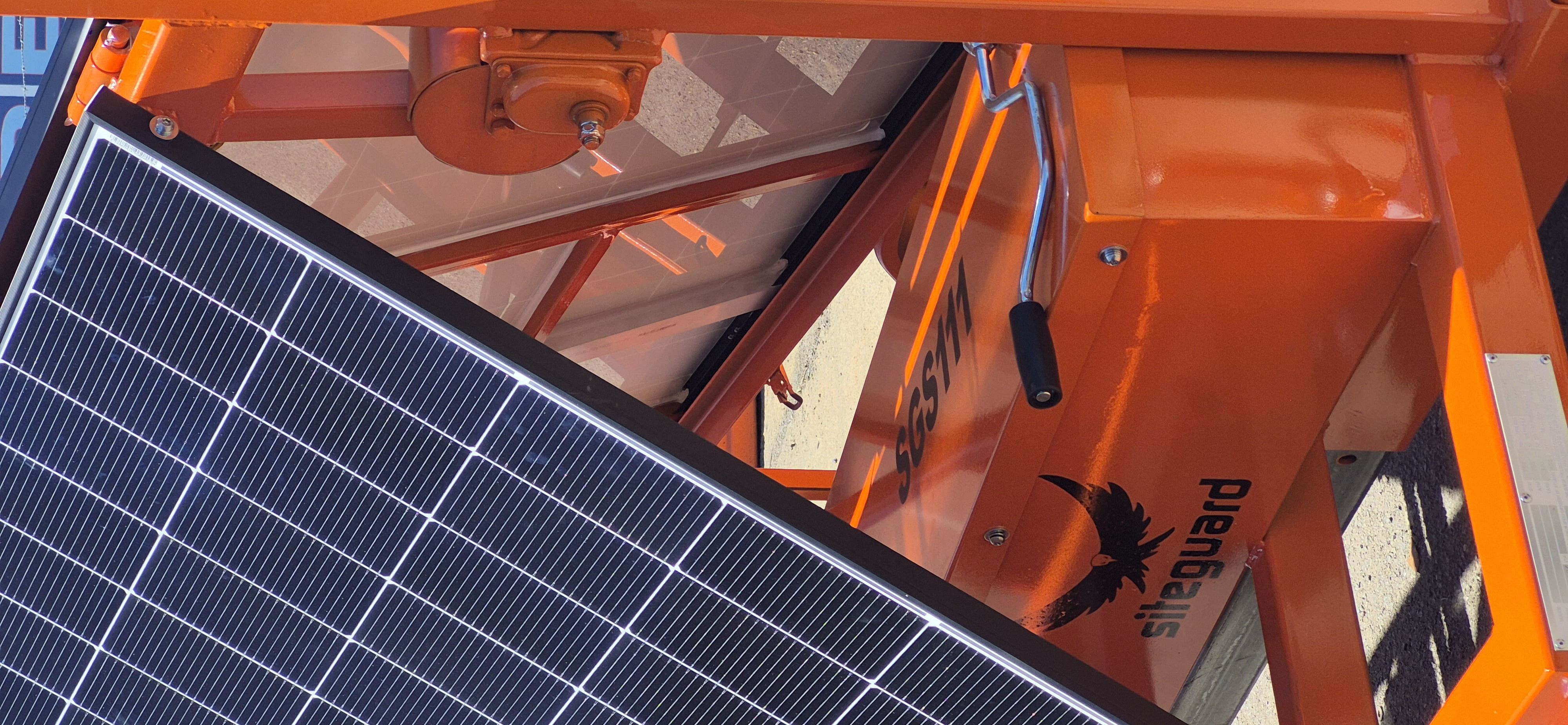 Close-up of a solar panel beside the mast winch on an orange Siteguard unit carrying the Siteguard logo
