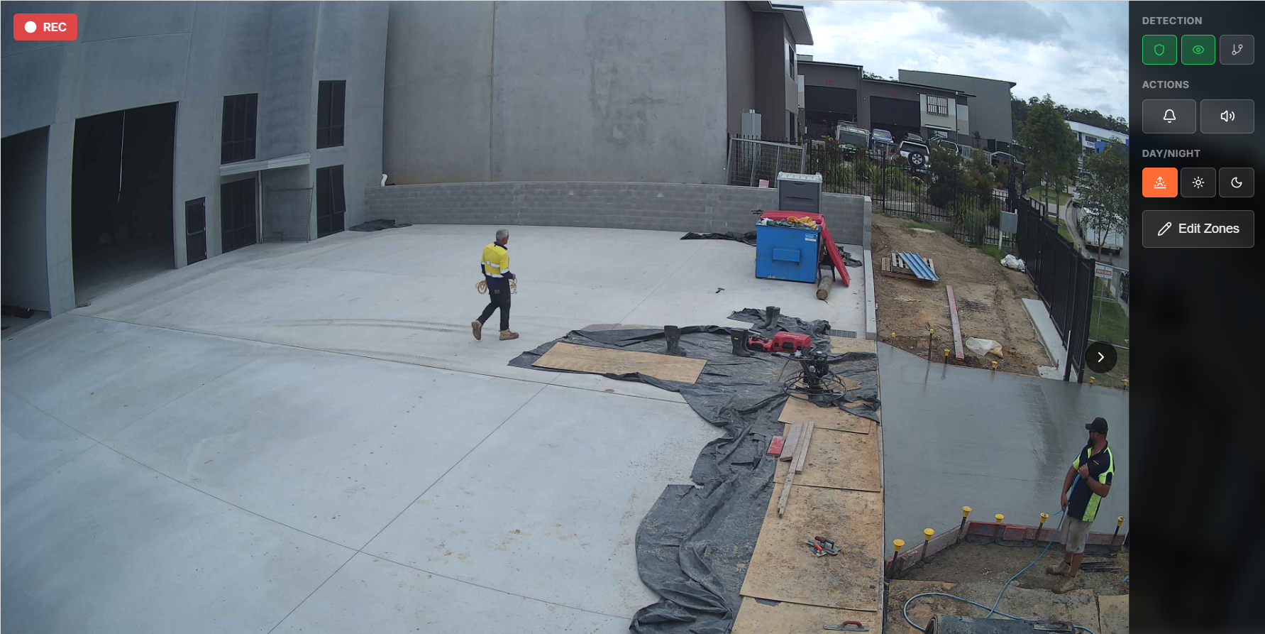 Live site camera view of a finished slab and a fresh concrete pour, with two workers, tools and recording, detection and action controls on screen