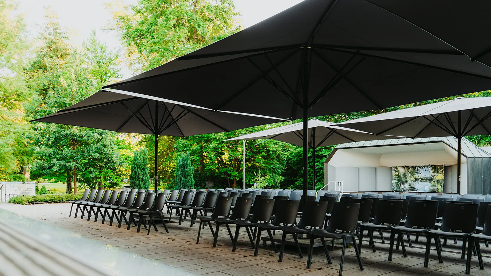 Flexibel anpassbare Stuhlreihen unter großen Sonnenschirmen, ideal für variabel große Sommerveranstaltungen und Open-Air-Events im Kurhaus Bad Bevensen.