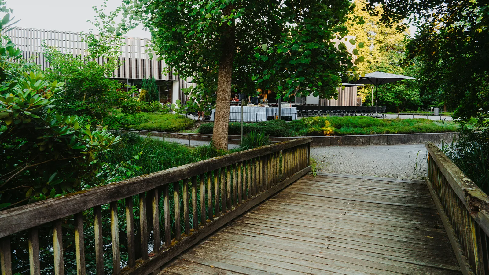 Malerische Holzbrücke, die die Naturverbundenheit und die direkte Nähe der Kurterrasse zum grünen Kurpark in Bad Bevensen unterstreicht.