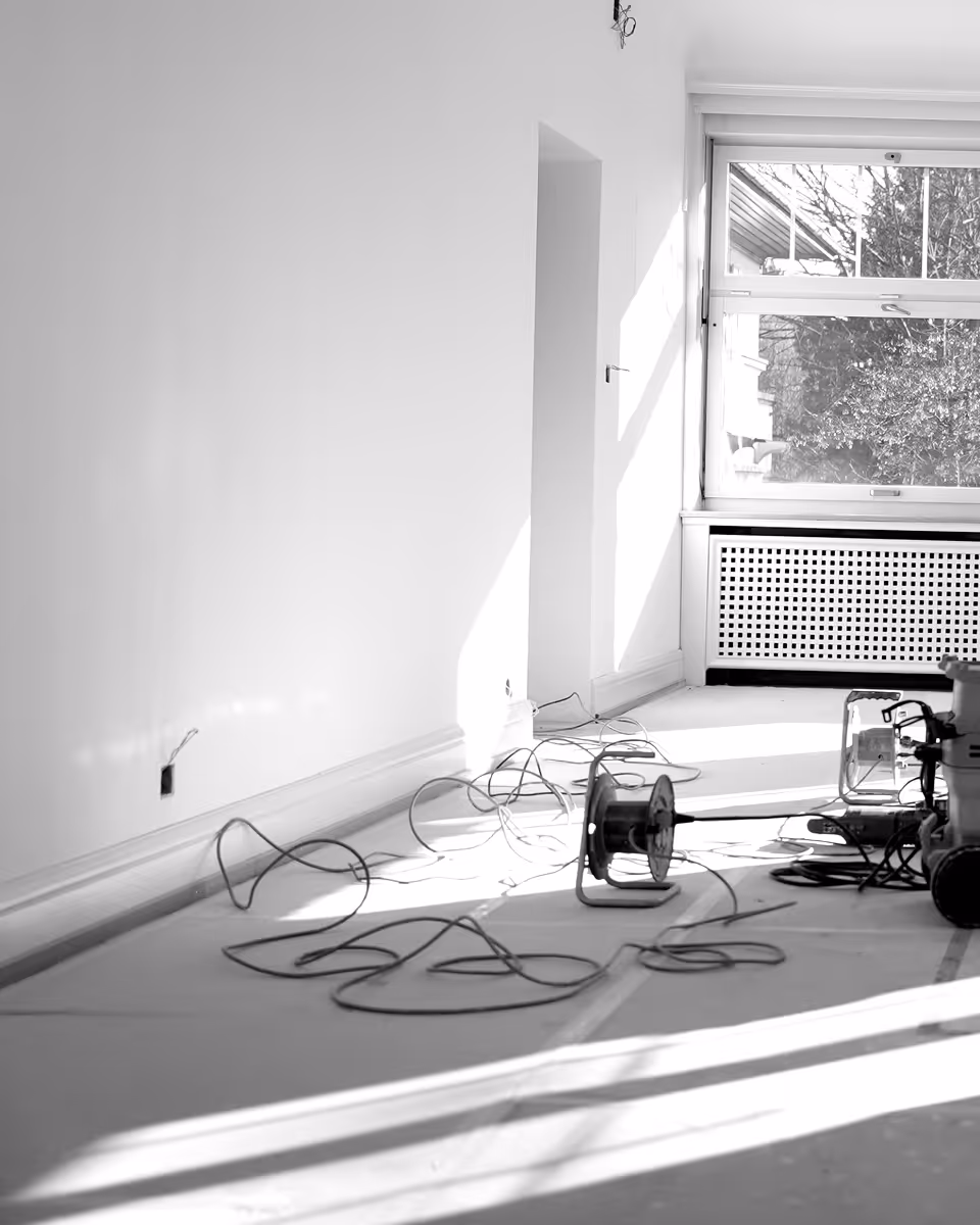 Ein leerer Raum im weißen Anstrich mit Elektrizitätskabeln und Werkzeugen auf dem Boden.