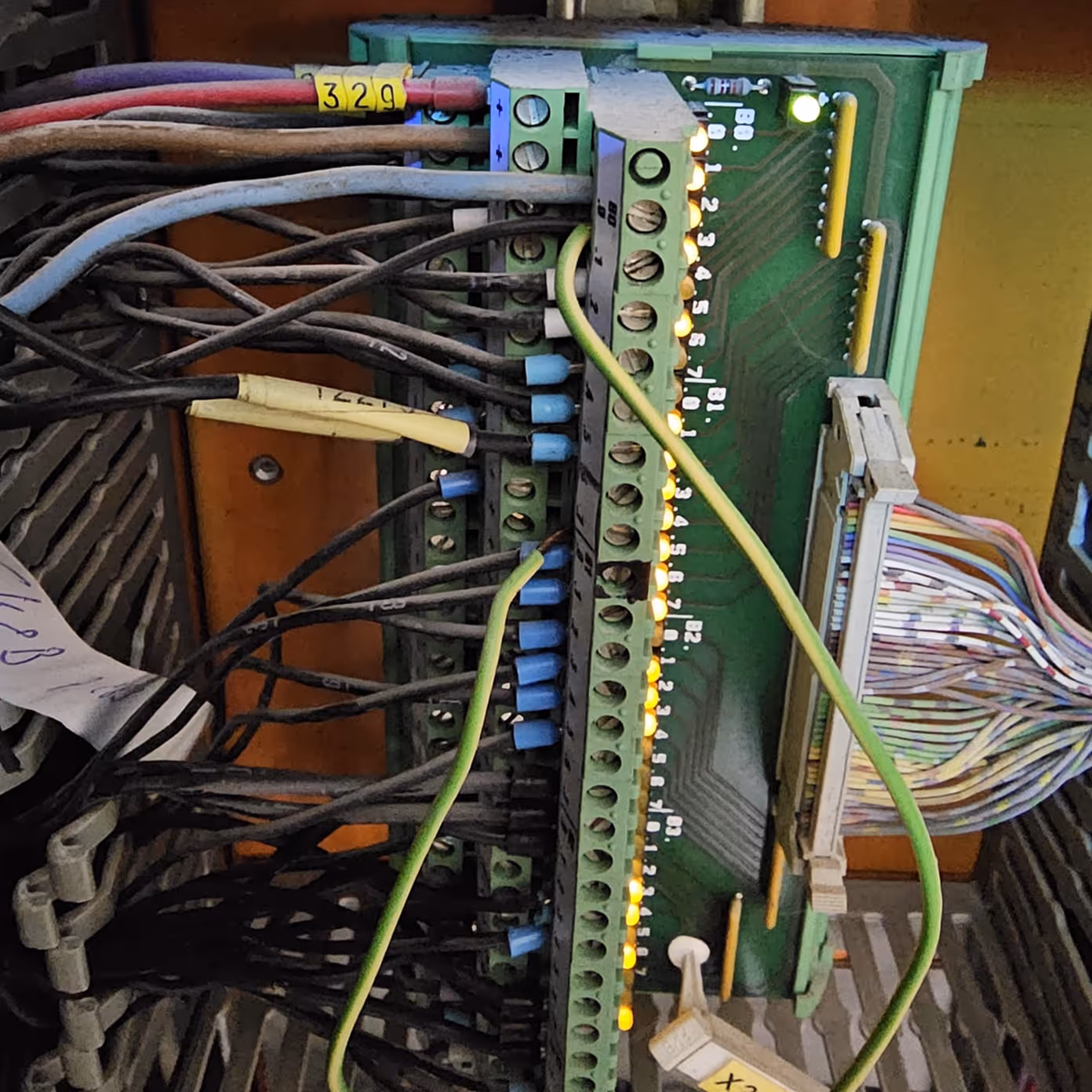 Close-up of a circuit board with multiple connected wires and illuminated indicator lights.