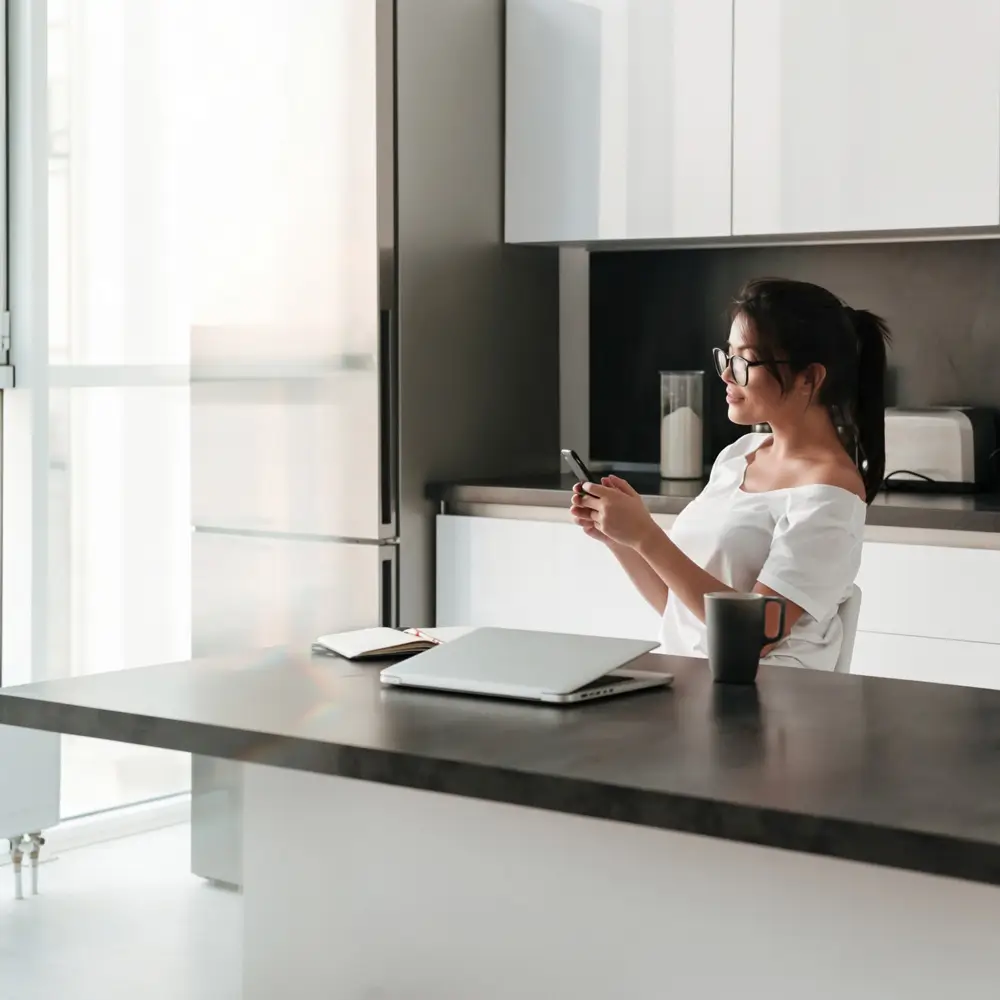 Sydney homeowner booking a professional cleaning service on her phone from a clean modern kitchen