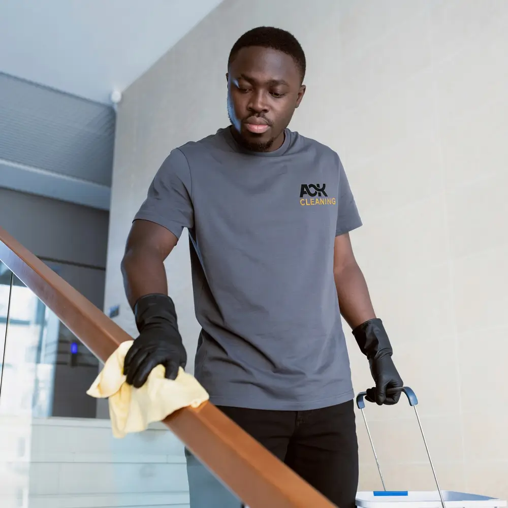 A OK Cleaning team member wiping down a stairwell handrail in a Sydney strata building