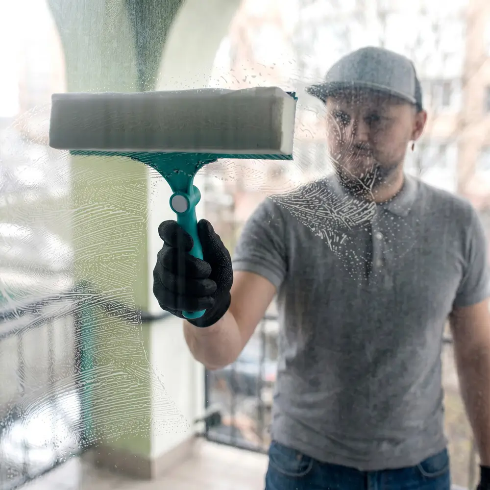 A OK Cleaning team member using a squeegee to clean a glass window in Sydney