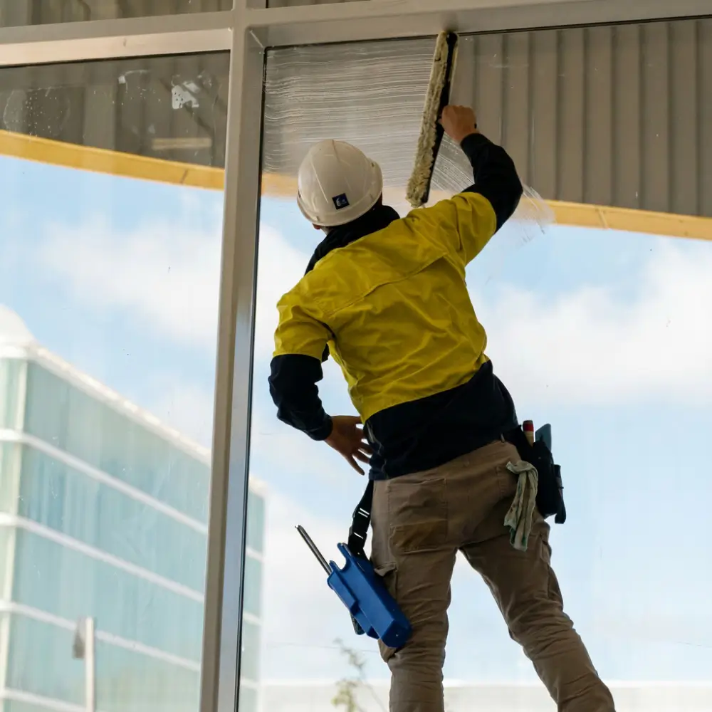 A OK Cleaning team member removing protective film from windows during a builders clean at a Sydney commercial property