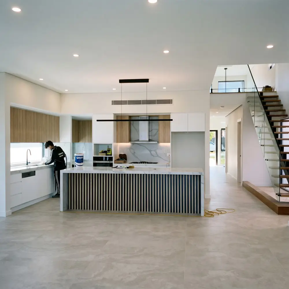 A OK Cleaning team member completing a builders clean in a newly constructed Sydney home with open plan kitchen and staircase