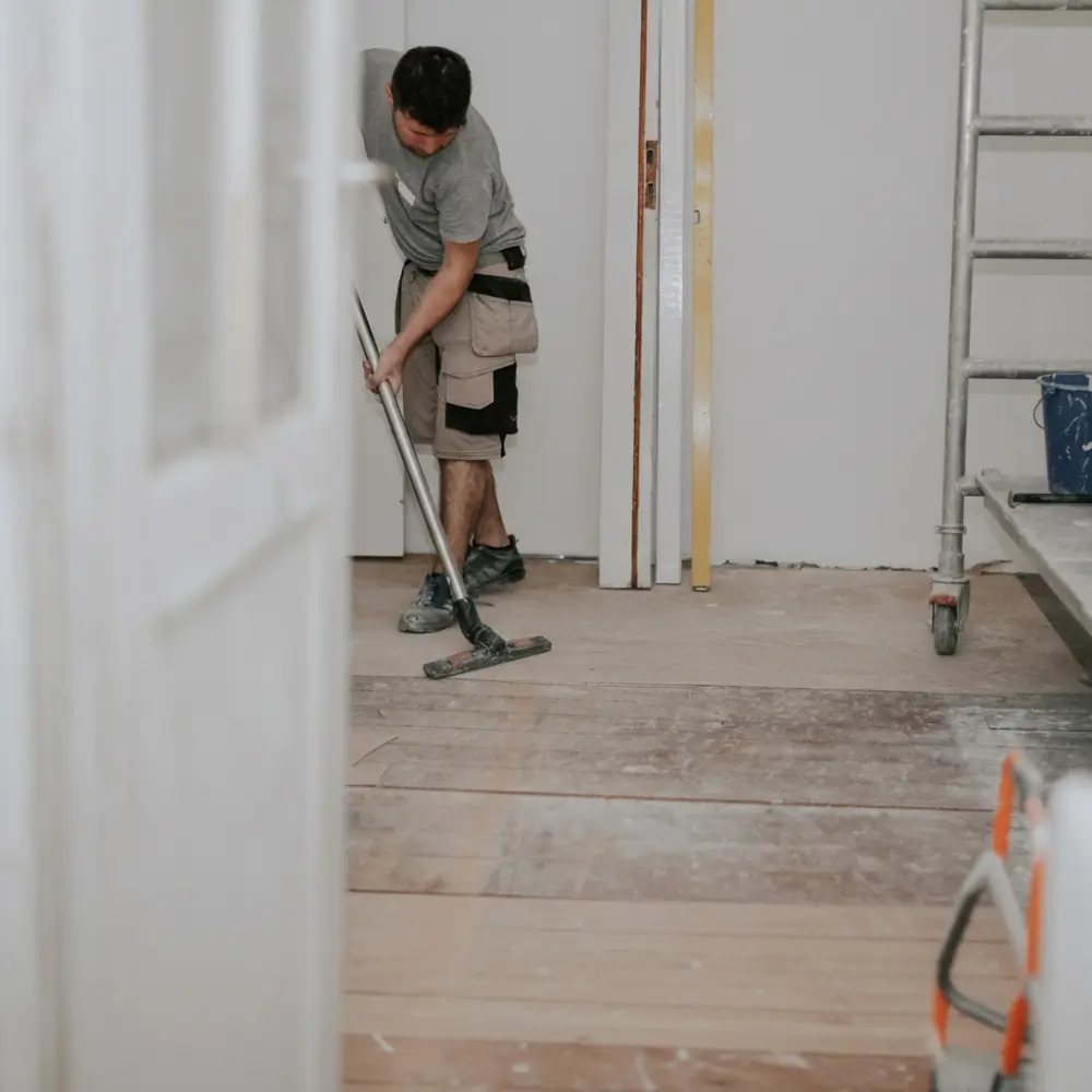 A OK Cleaning team member sweeping construction dust and debris from hardwood floors during a builders clean in a Sydney renovation