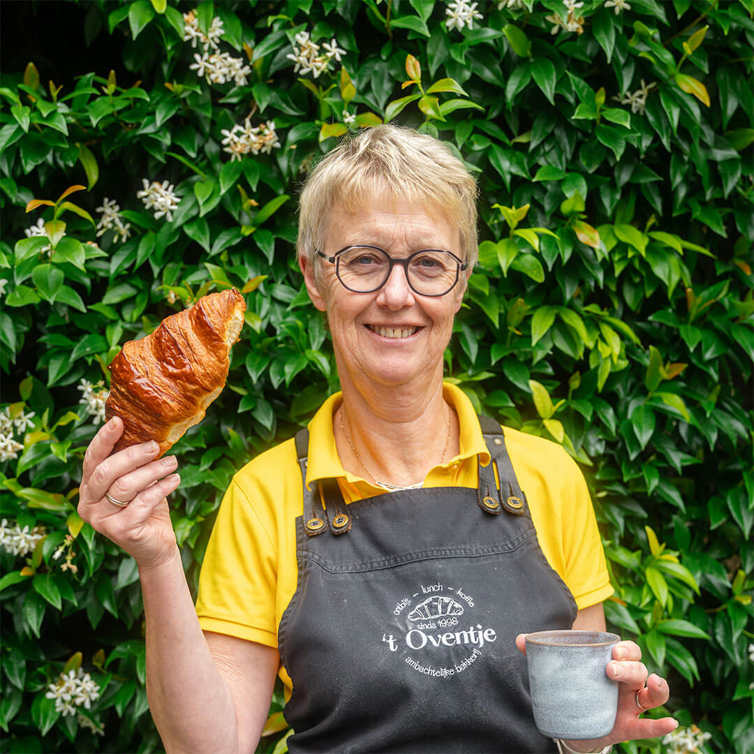 Foto van Veerle met koek en koffie in de hand. Ze is verkoopster bij bakkerij 't Oventje