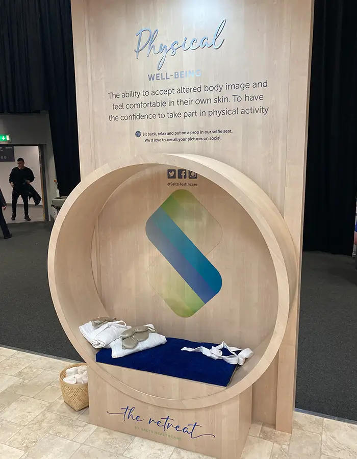 Interactive booth inviting people to accept body image and join physical activity with a circle seat and props.