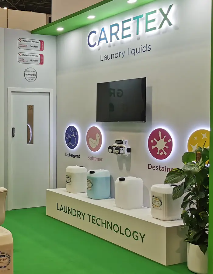 Trade show booth with CARETEX laundry liquids, detergent, softener, and destainer products on display.