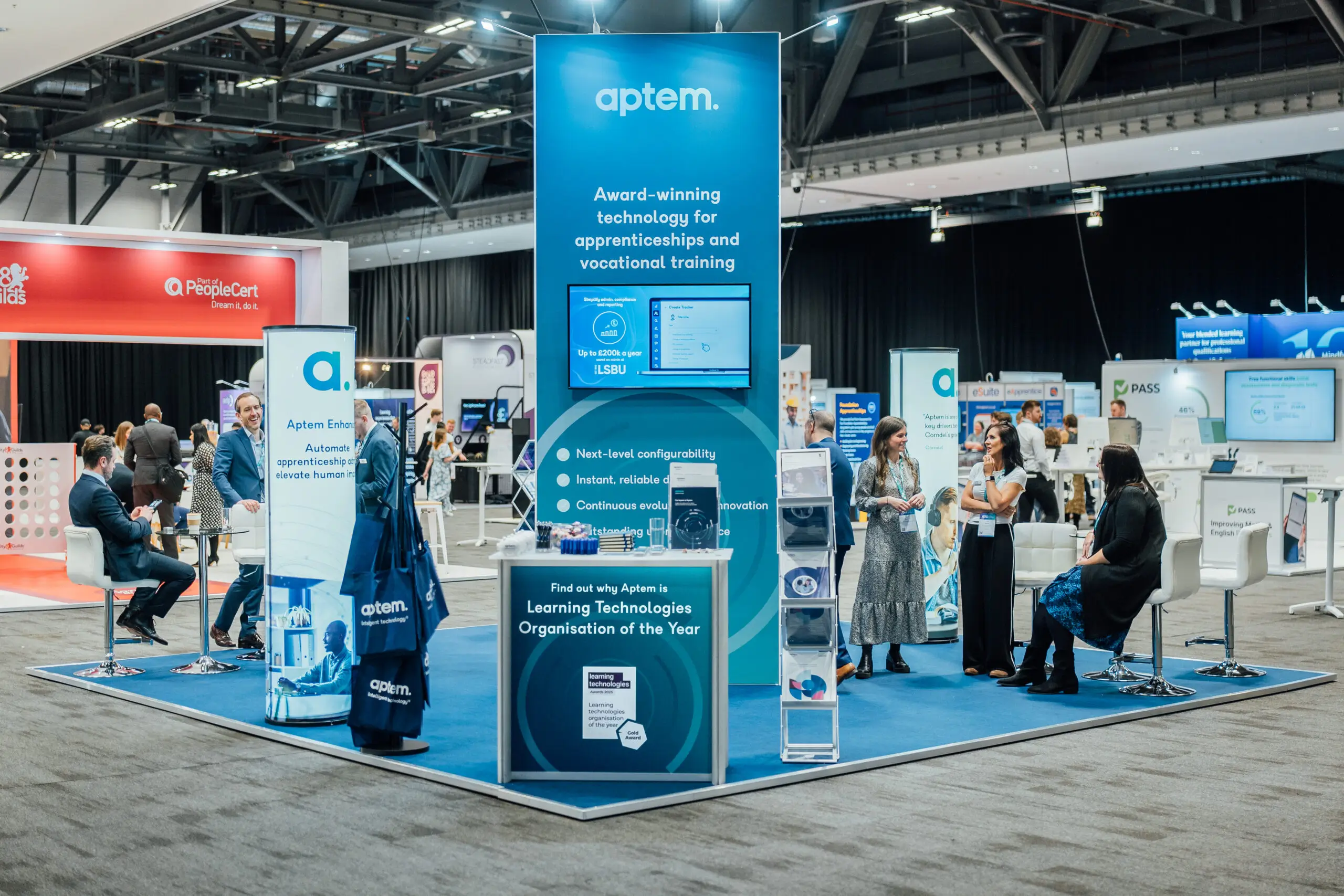 Aptem trade show booth with banners, staff engaging and information on apprenticeship technology.