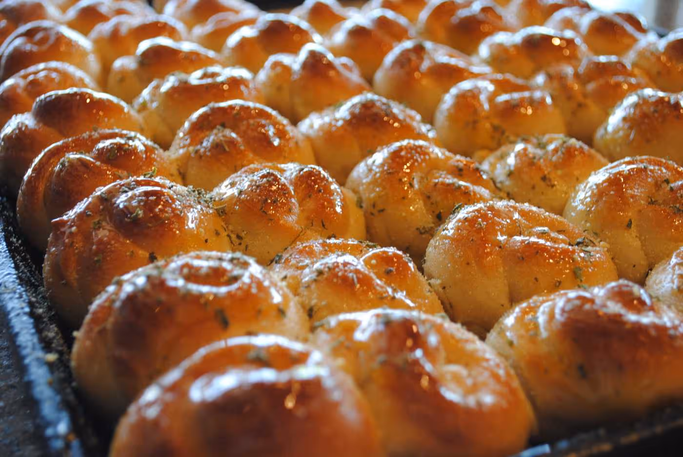 Tray of golden brown garlic herb dinner rolls fresh from the oven.