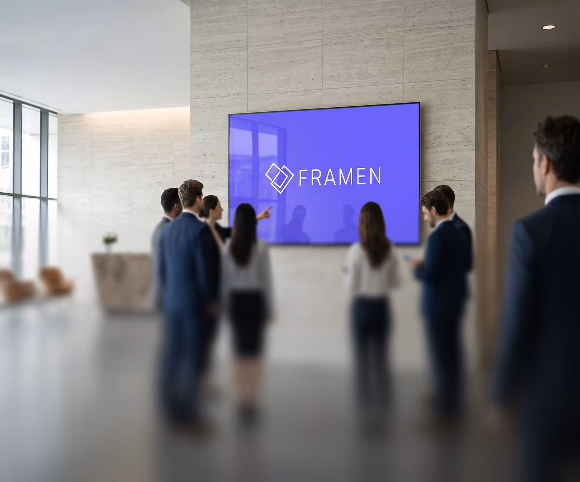 Un groupe de professionnels regardant un écran arborant le FRAMEN dans un immeuble de bureaux moderne.