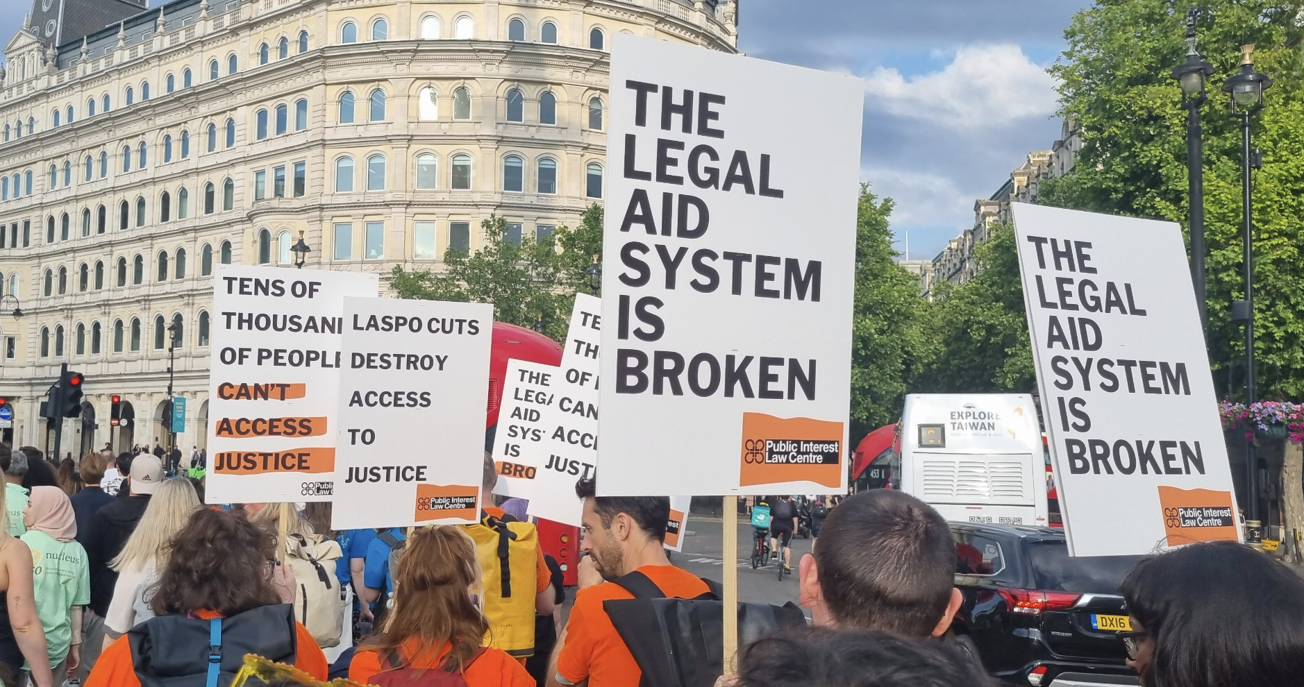 Placards taht read "The Legal Aid System is Broken" with Public Interest Law Centre (PILC) logos