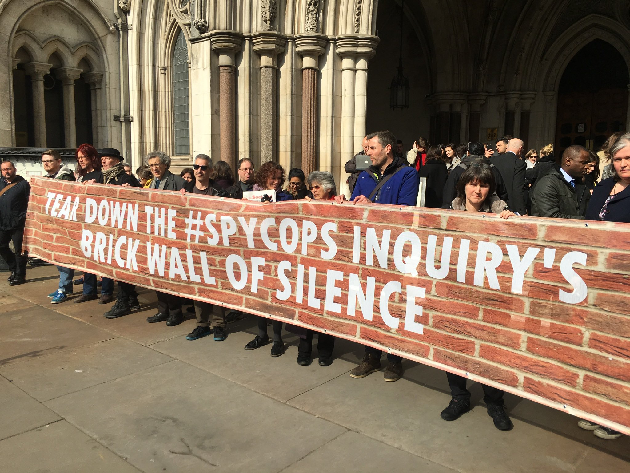 Protesters outside the Royal Courts of Justice with a banner reading 'Tear down the #Spycops Inquiry's brick wall of silence'