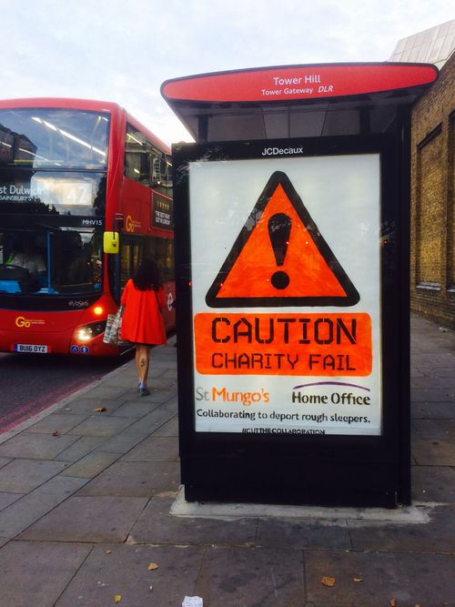 A bus-stop advert altered with a 'Caution: Charity Fail — St Mungo's and Home Office collaborating to deport rough sleepers' campaign sticker