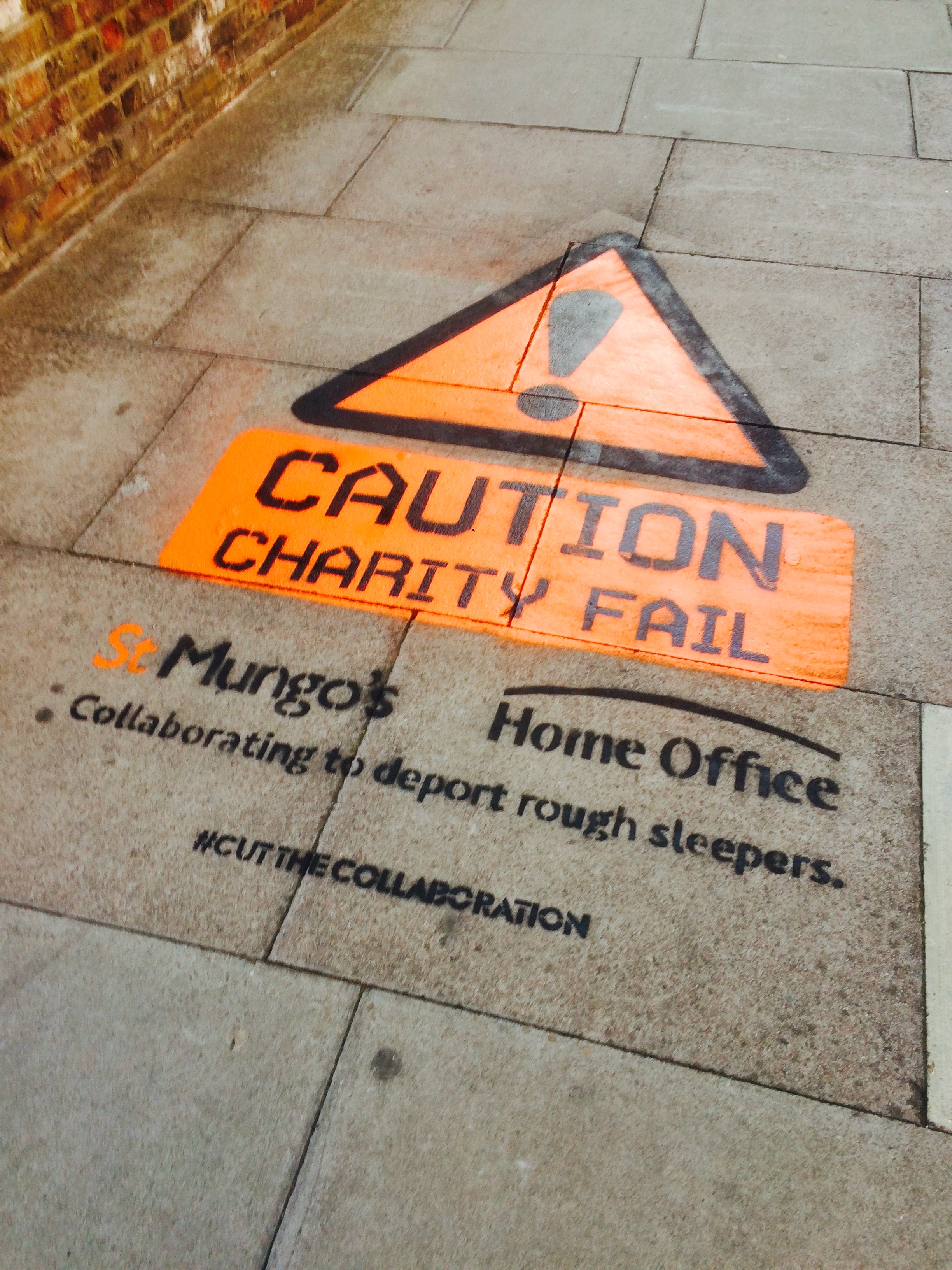 The 'Caution: Charity Fail' campaign stencilled onto a pavement, protesting the St Mungo's and Home Office rough sleeper data-sharing arrangement