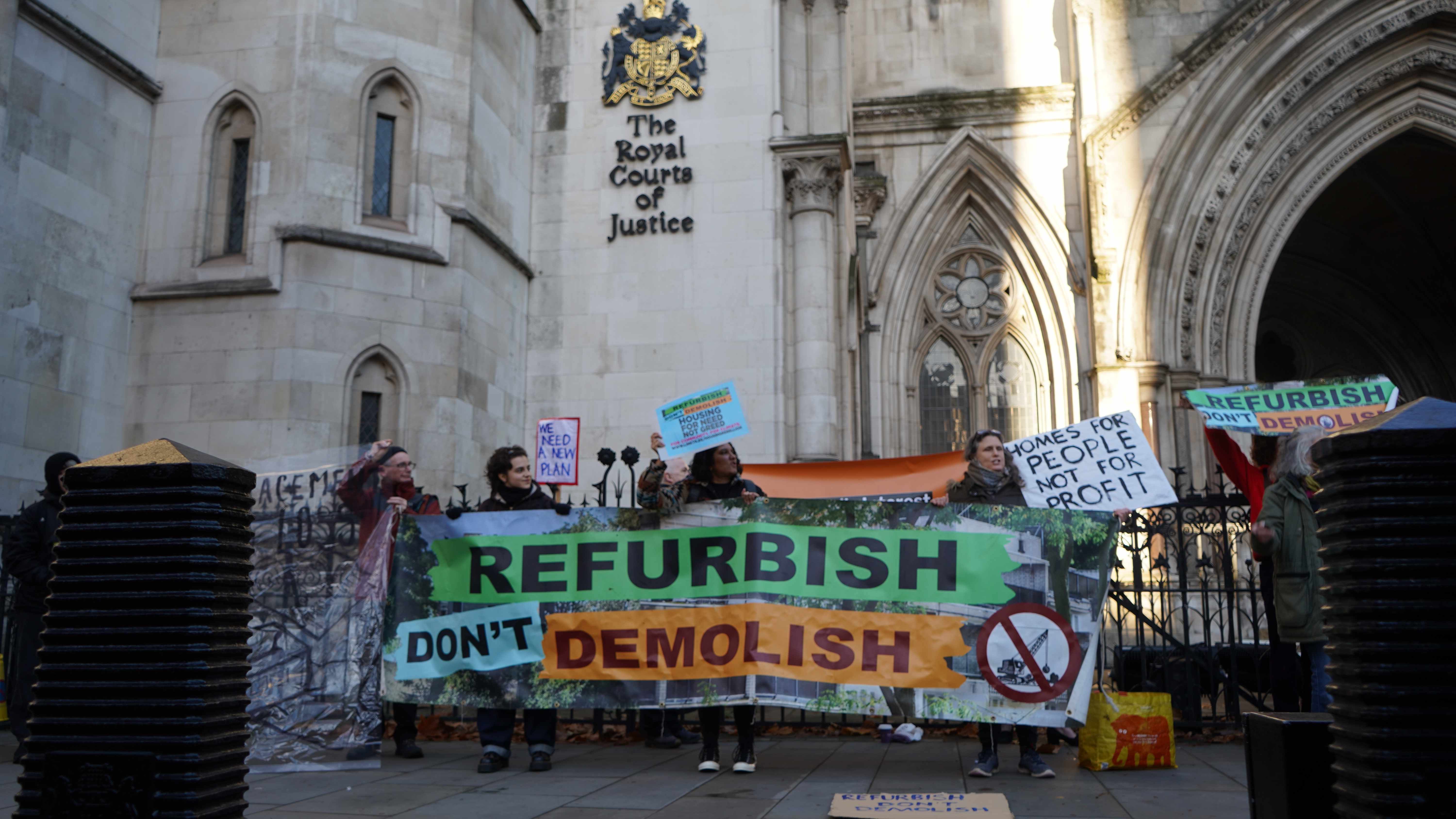 A campaigner outside the Royal Courts of Justice holding a 'Hands off our homes' placard