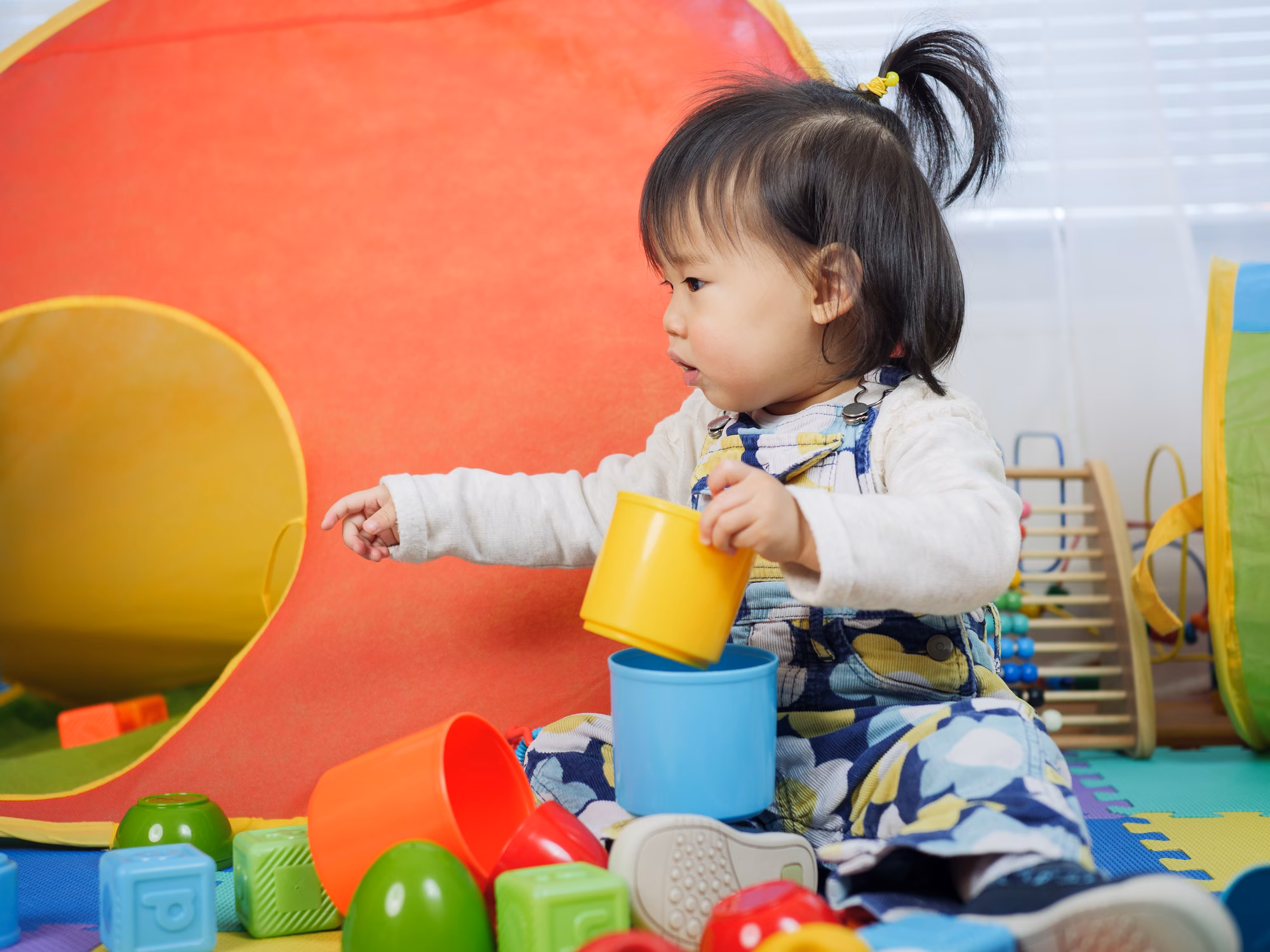 Toddler playing with colourful stacking cups
