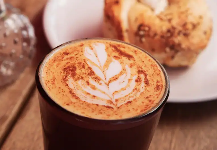 Cup of coffee with leaf latte art and cinnamon on top