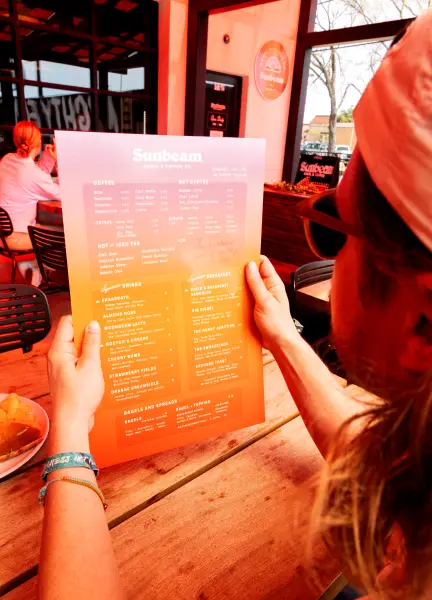 Person holding the sunbeam menu while sitting on the patio